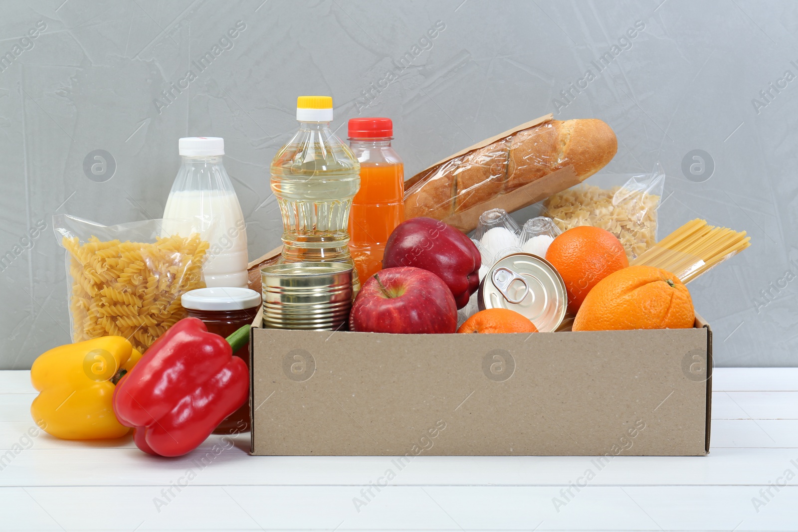 Photo of Humanitarian aid. Different food products for donation in box on white wooden table