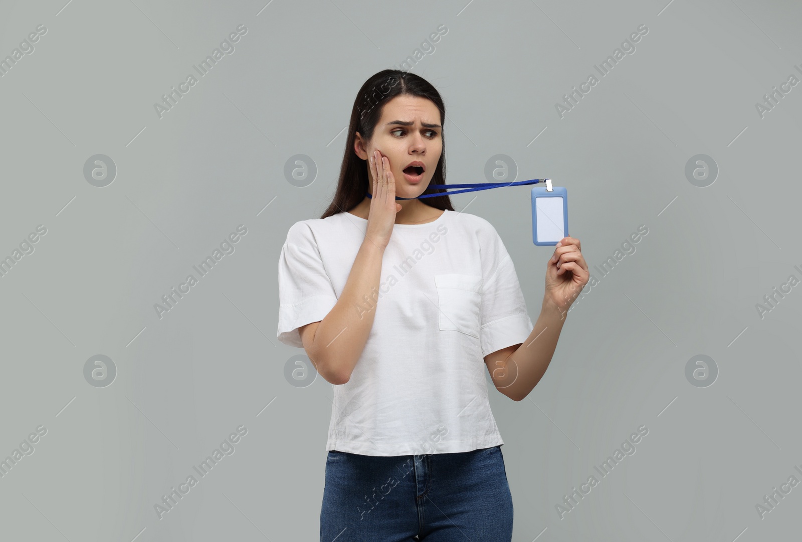 Photo of Emotional woman holding vip pass badge on grey background