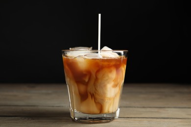 Photo of Pouring milk into glass with coffee on wooden table