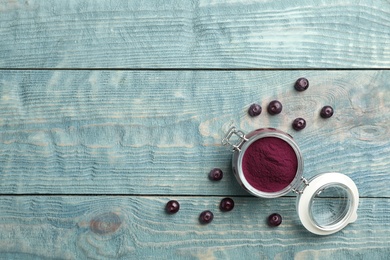 Jar of acai powder and fresh berries on wooden table, flat lay with space for text