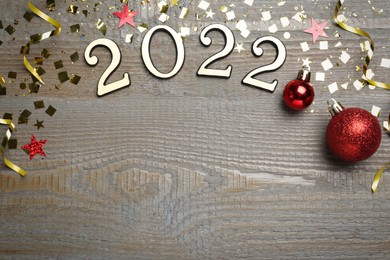 Photo of Flat lay composition with number 2022 and festive decor on wooden background, space for text. Happy New Year