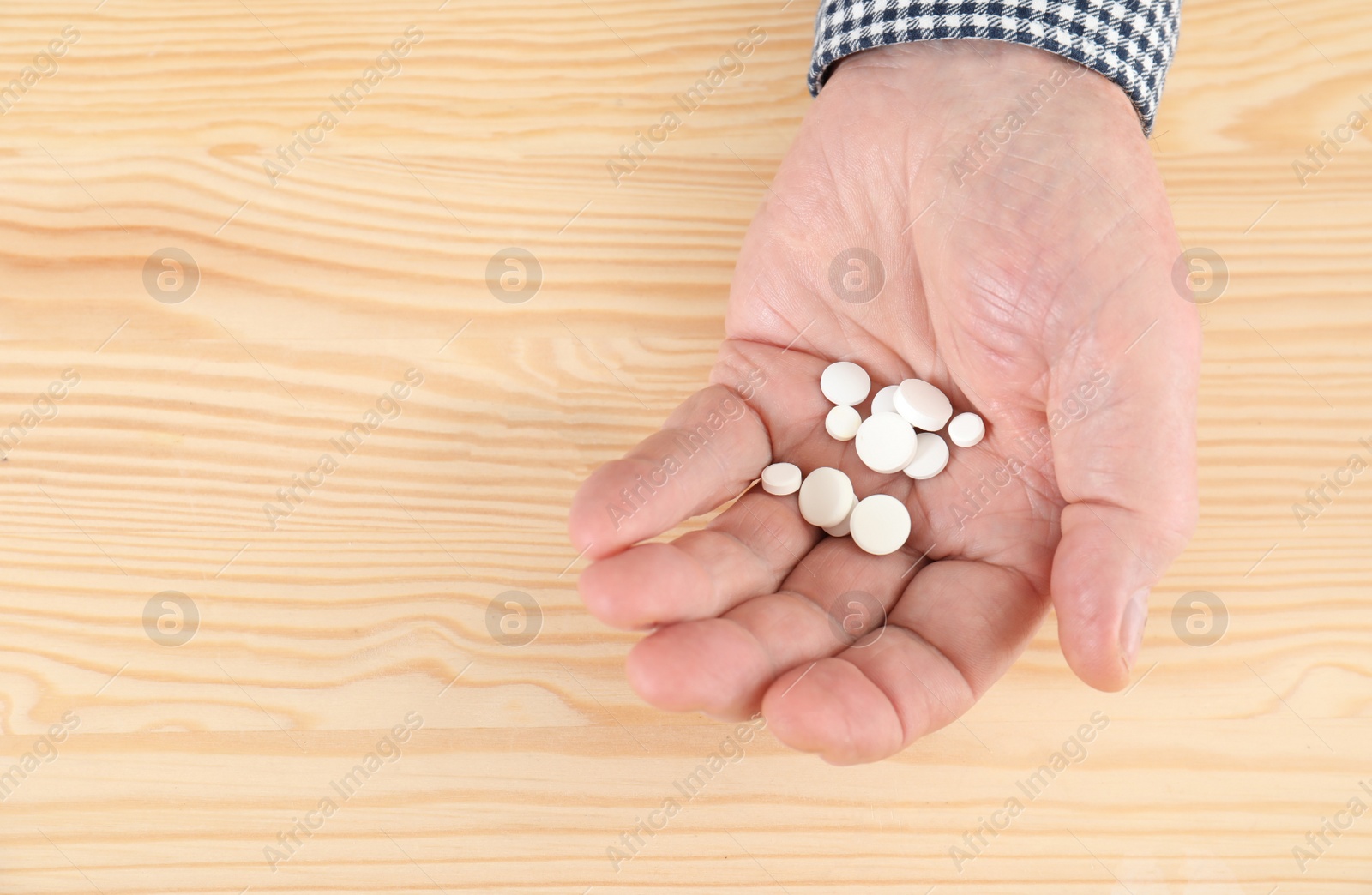 Photo of Senior man holding pills in hand at table, top view. Space for text
