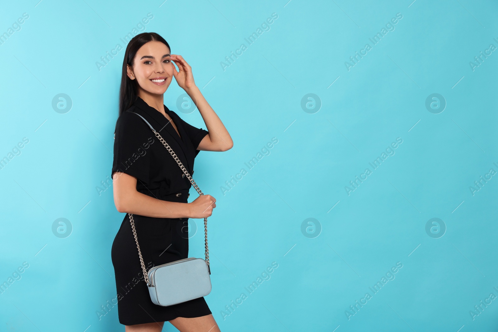 Photo of Beautiful young woman with stylish bag on light blue background, space for text