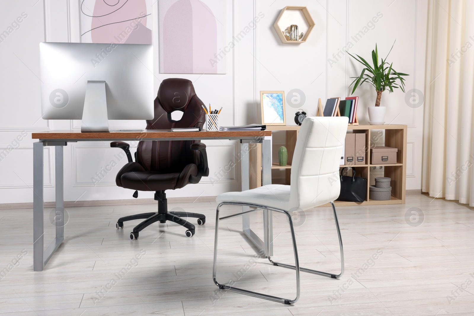 Photo of Director's workplace with wooden table, computer and comfortable armchairs. Interior design