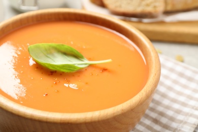 Photo of Tasty creamy pumpkin soup with basil in bowl on table, closeup