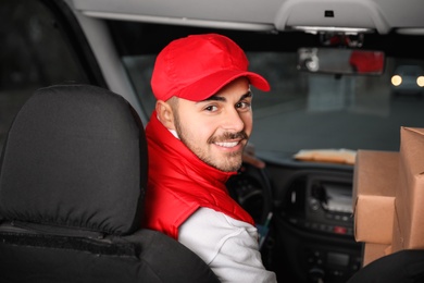 Photo of Deliveryman in uniform with parcels in car