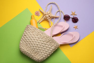 Stylish bag with beach accessories on color background, flat lay