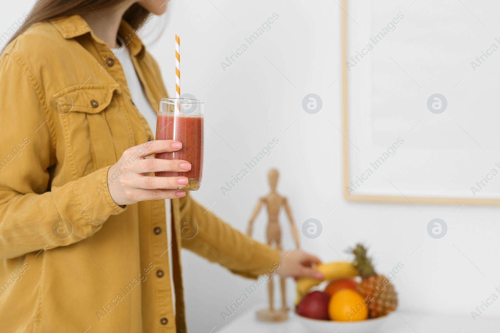 Photo of Woman with delicious smoothie taking fruit at home, closeup. Space for text