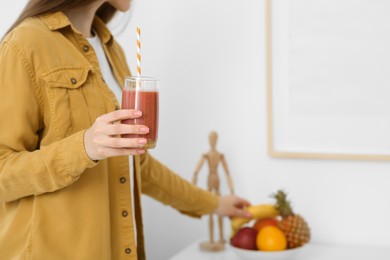 Woman with delicious smoothie taking fruit at home, closeup. Space for text