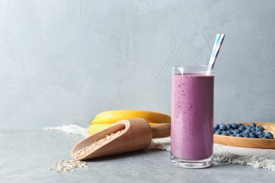 Glass with blueberry smoothie on grey table