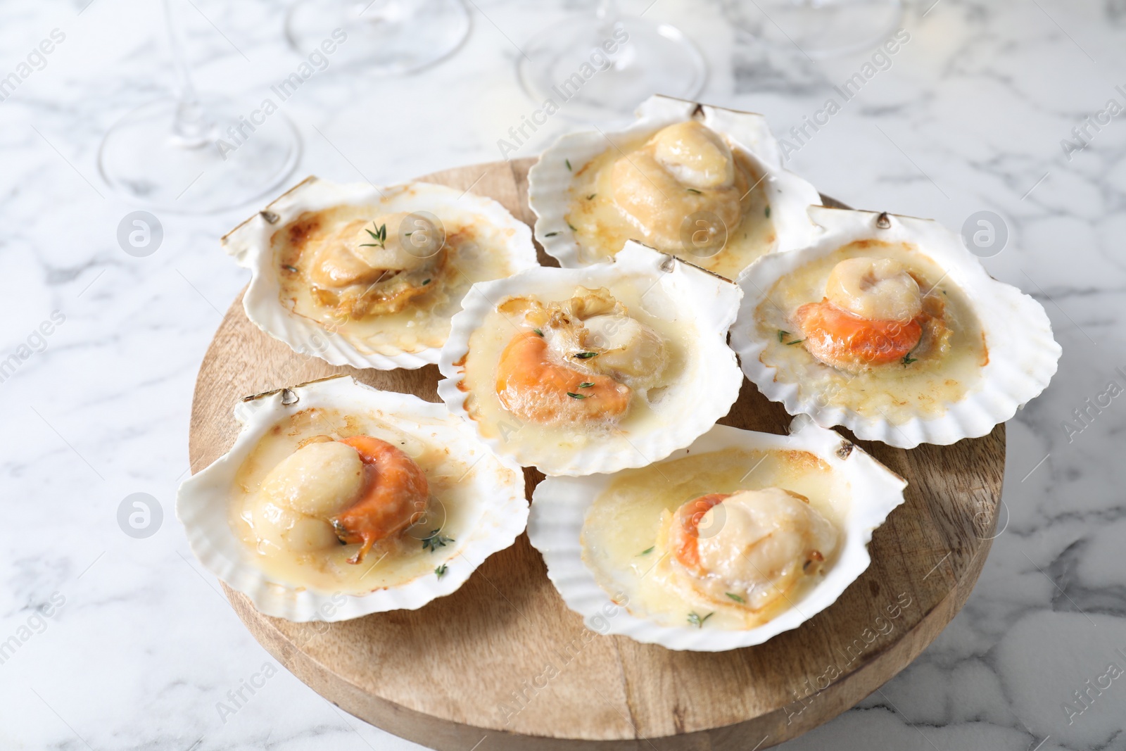 Photo of Fried scallops in shells on white marble table, closeup