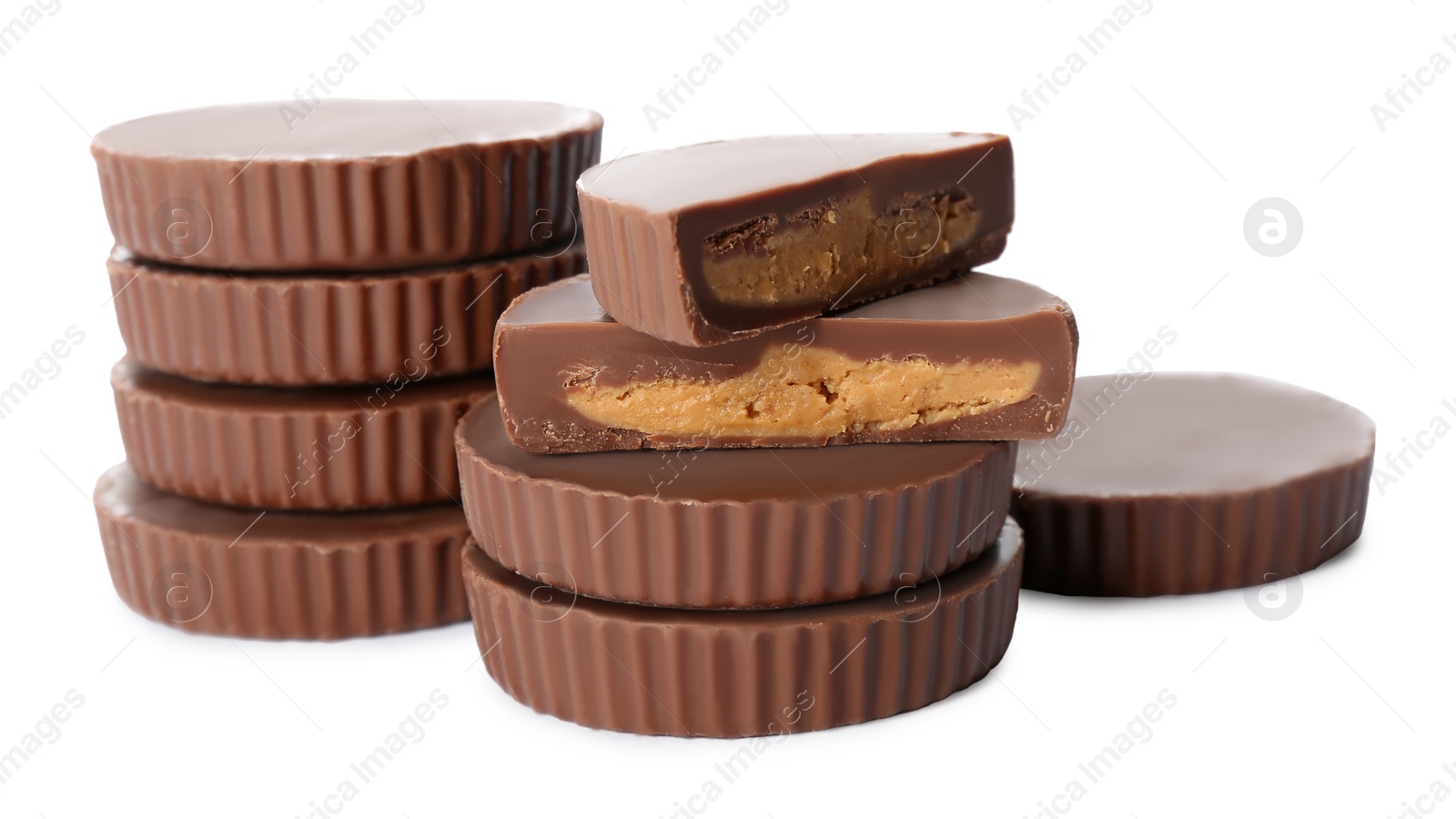 Photo of Cut and whole delicious peanut butter cups on white background