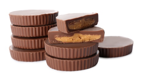 Cut and whole delicious peanut butter cups on white background