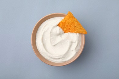 Photo of Delicious tofu sauce served with nachos chip in bowl on grey background, top view