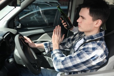 Photo of Driver refusing from alcohol while woman suggesting him beer in car, closeup. Don't drink and drive concept