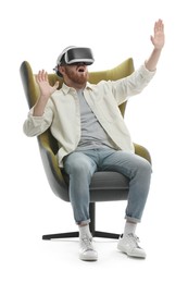 Photo of Emotional man using virtual reality headset while sitting in armchair on white background