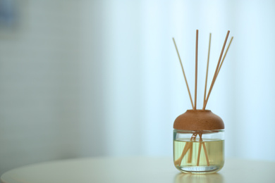 Aromatic reed air freshener on table indoors. Space for text