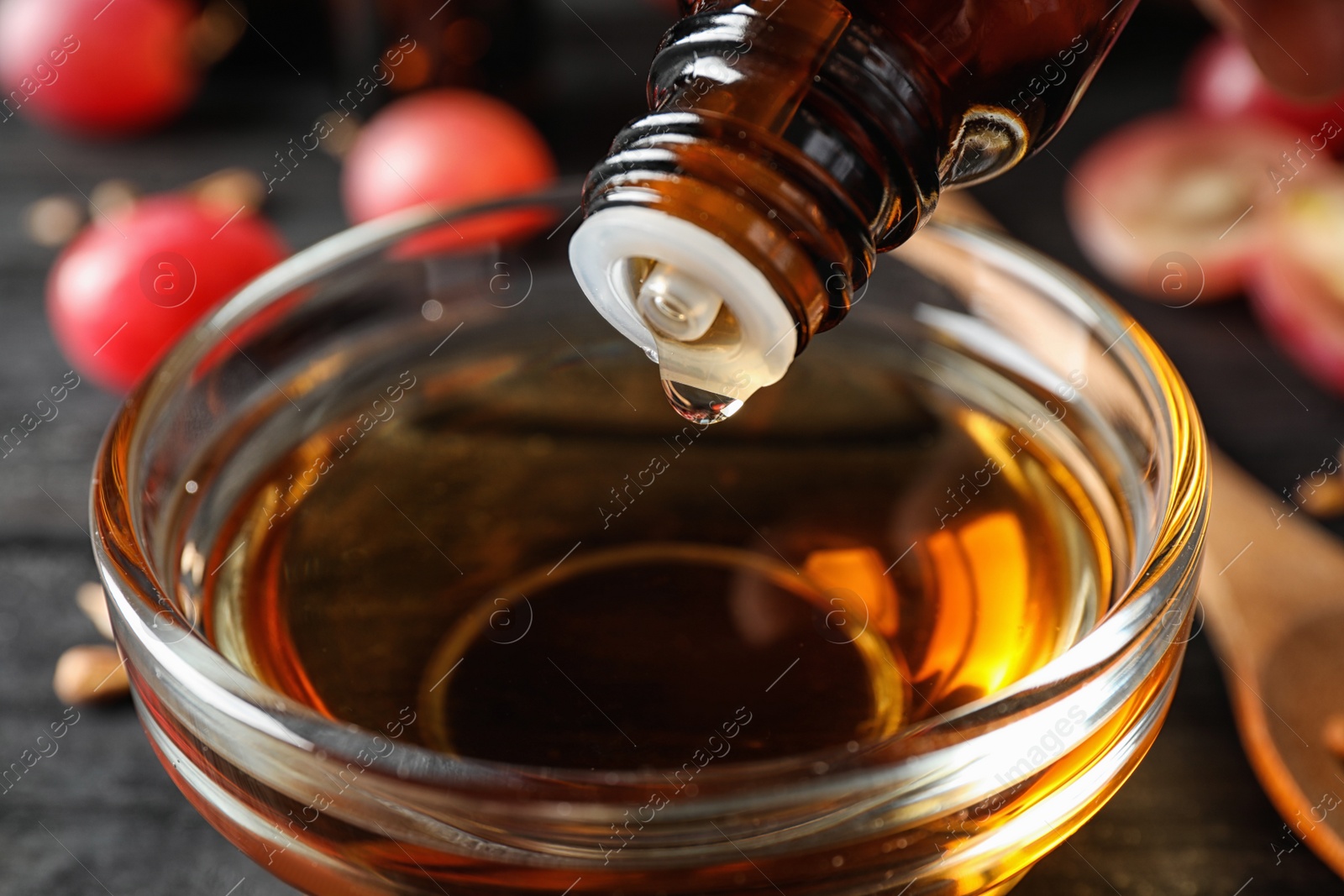 Photo of Dripping natural grape seed oil into glass bowl on table, closeup. Organic cosmetic