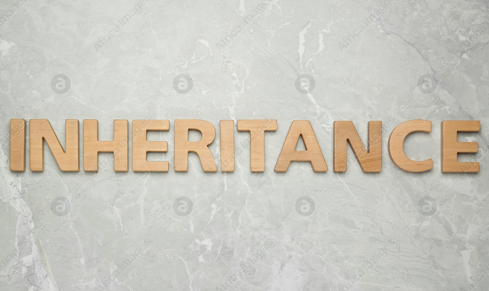 Photo of Word Inheritance made with wooden letters on light marble background, flat lay