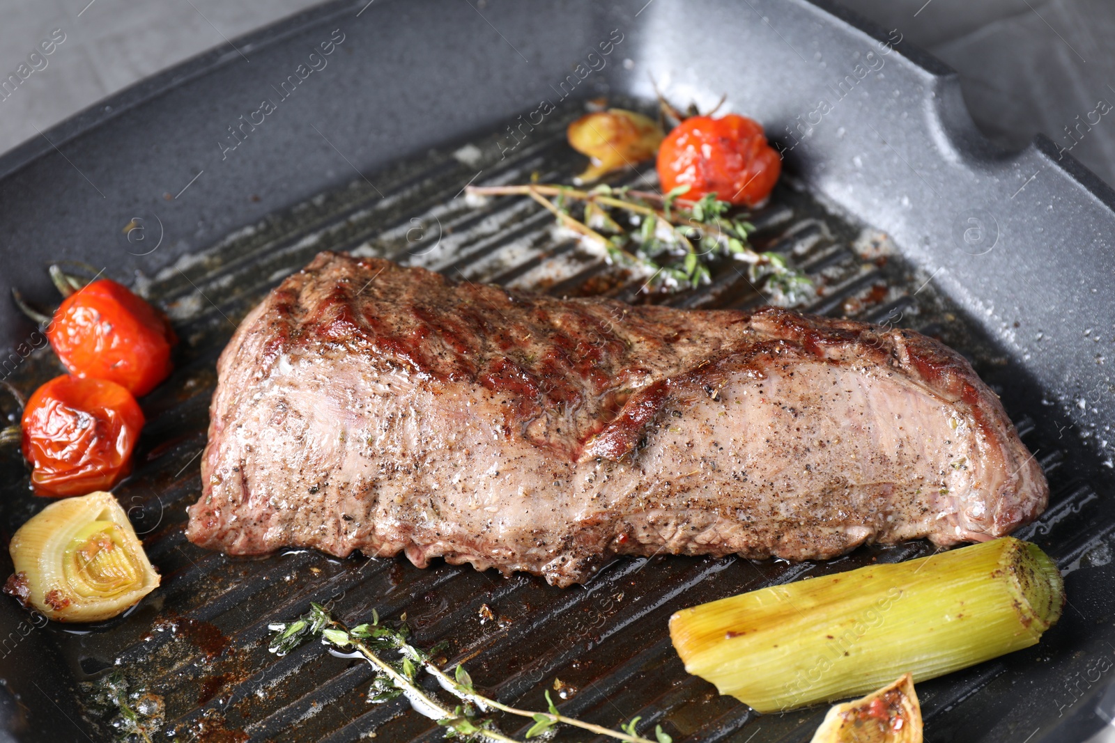 Photo of Delicious grilled beef meat and vegetables in pan on table, closeup