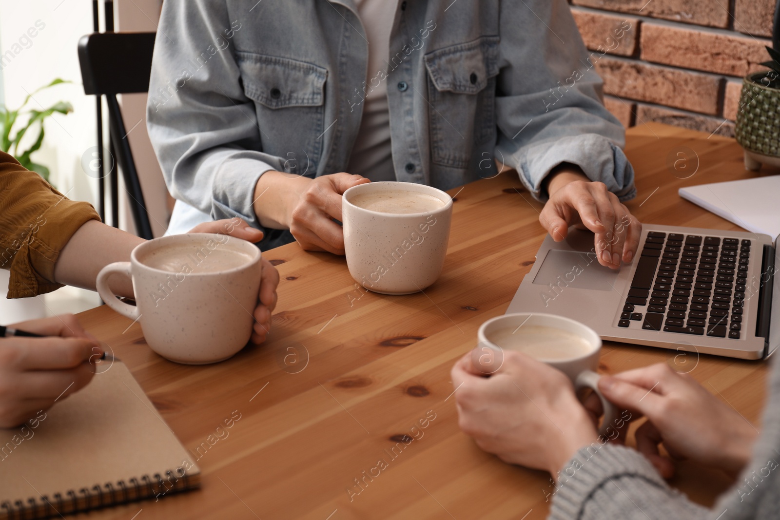 Photo of Women with cups of coffee at table in cafe, closeup