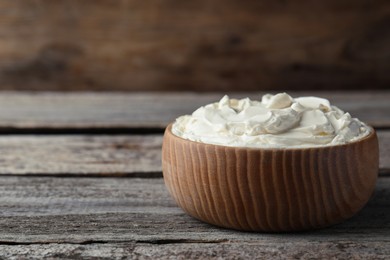 Photo of Bowl of tasty cream cheese on wooden table, space for text