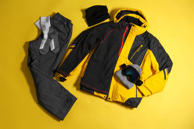 Photo of Stylish winter sport clothes on yellow background, flat lay