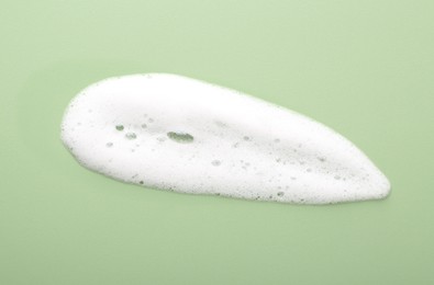 Photo of Sample of fluffy foam on green background, top view