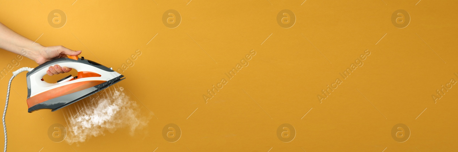 Image of Woman with iron on orange background, closeup. Banner design with space for text