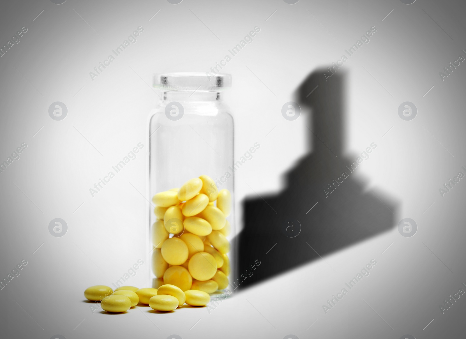 Image of Doping concept. Yellow pills in glass bottle with first place shadow on light background
