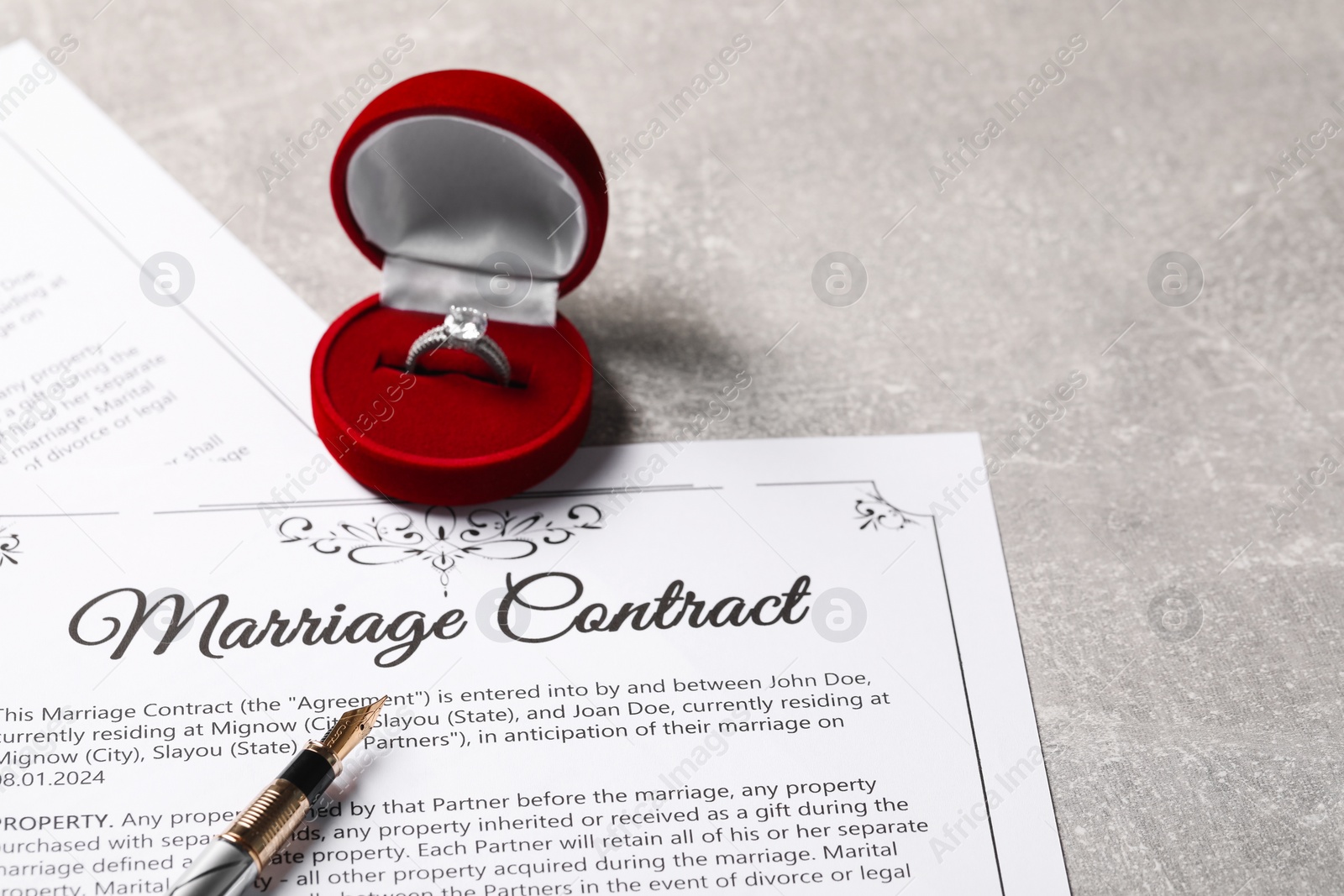 Photo of Marriage contract, fountain pen and ring with gemstone on grey table