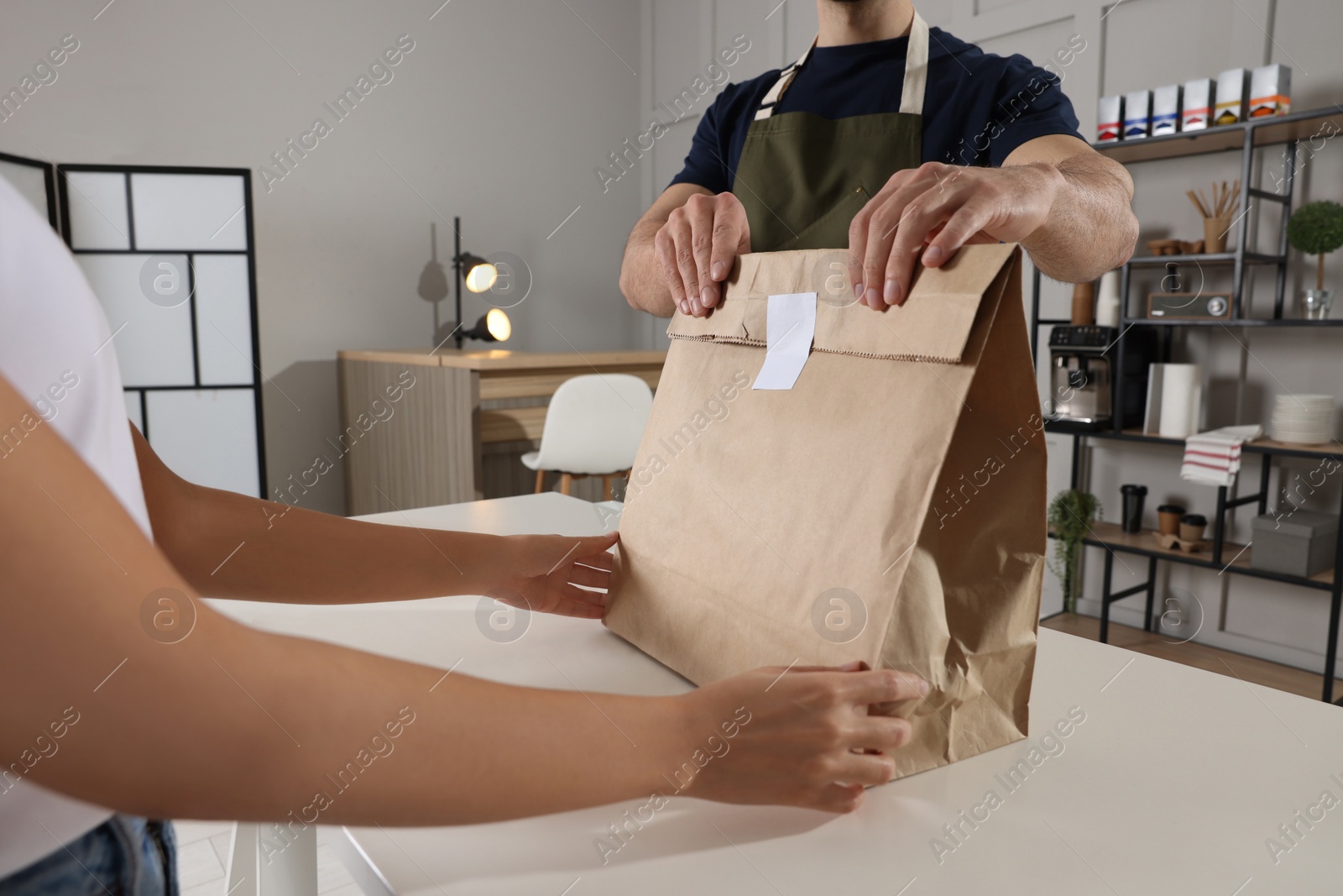 Photo of Worker giving paper bag to customer in cafe, closeup