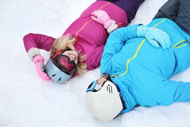 Photo of Couple lying on snow at ski resort. Winter vacation