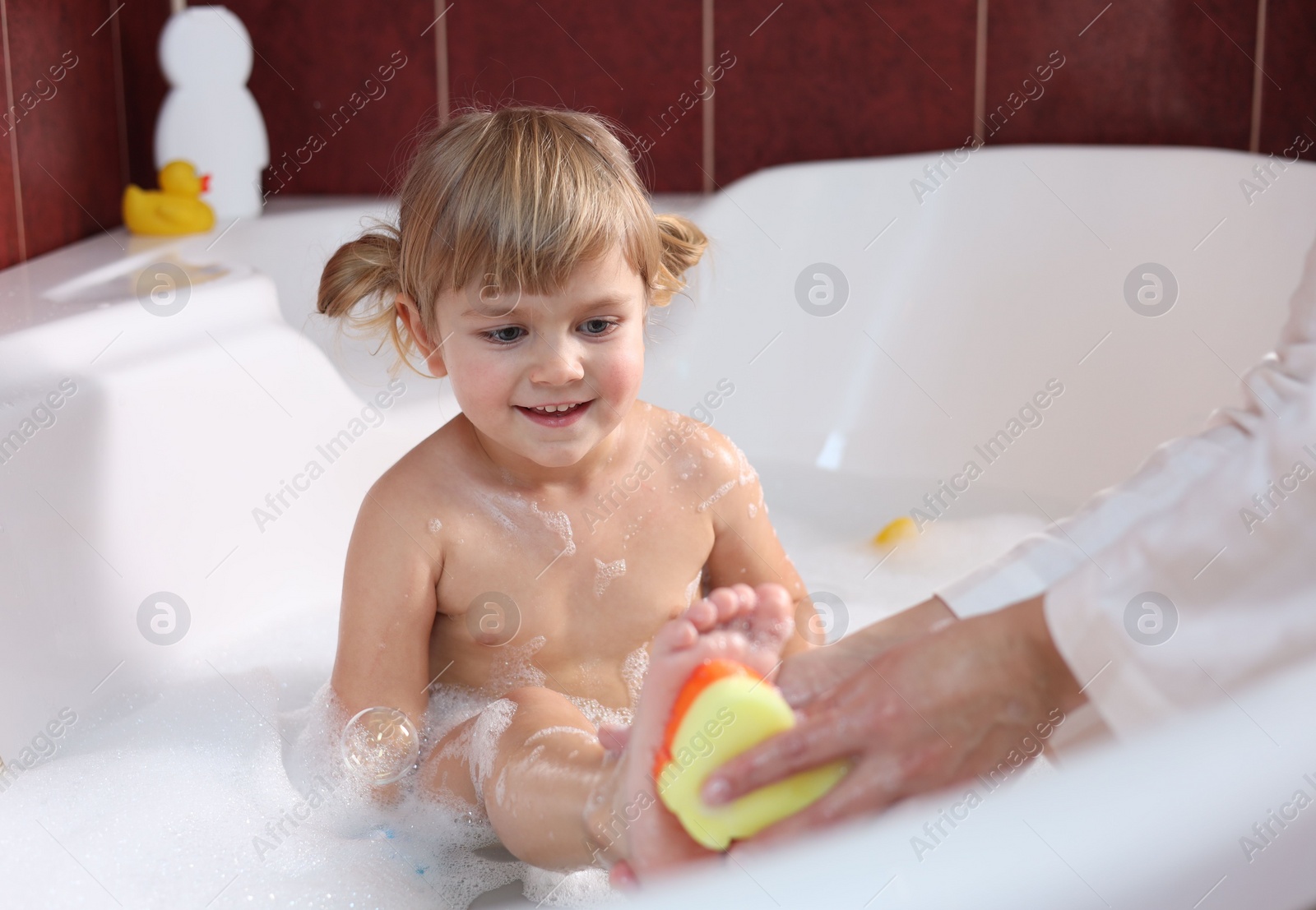 Photo of Mother washing her smiling daughter with sponge in bathtub, closeup