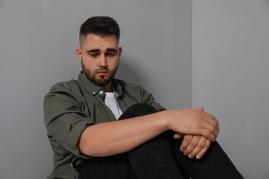 Portrait of sad man near light grey wall