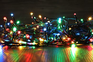 Photo of Beautiful colorful Christmas lights on wooden table