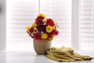 Photo of Beautiful bouquet and yellow cloth on white wooden table near window. Good morning