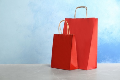 Mockup of paper shopping bags on table against color background