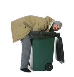 Poor homeless man digging in trash bin isolated on white