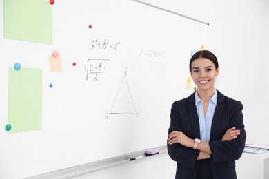 Photo of Young teacher near whiteboard in modern classroom. Space for text