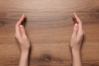 Photo of Woman holding on wooden table, closeup of hands. Space for text