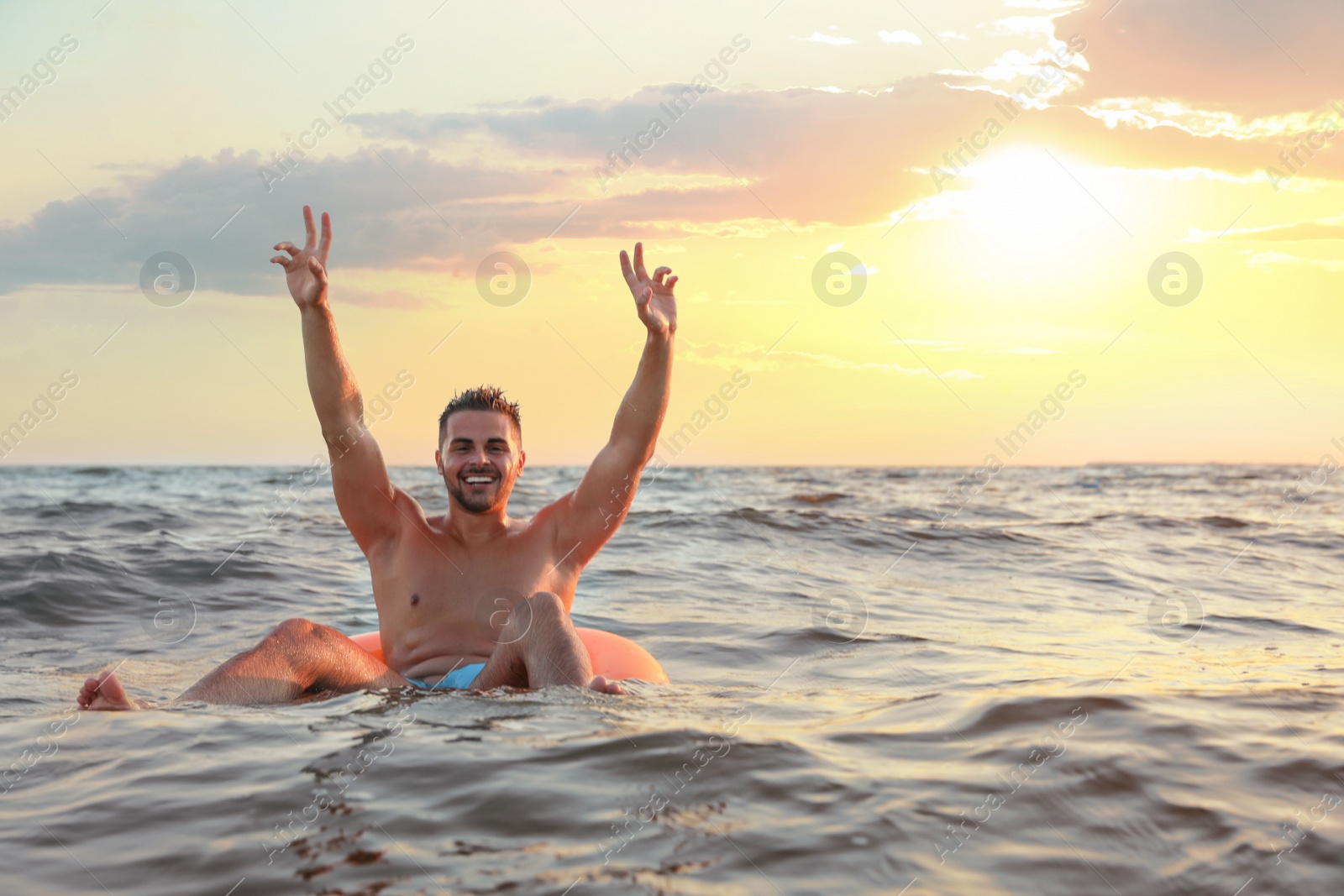 Photo of Happy young man on inflatable ring in water