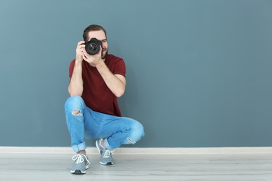Young photographer with professional camera near color wall