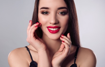 Beautiful woman with stylish nail polish on grey background