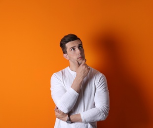 Thoughtful handsome young man on color background