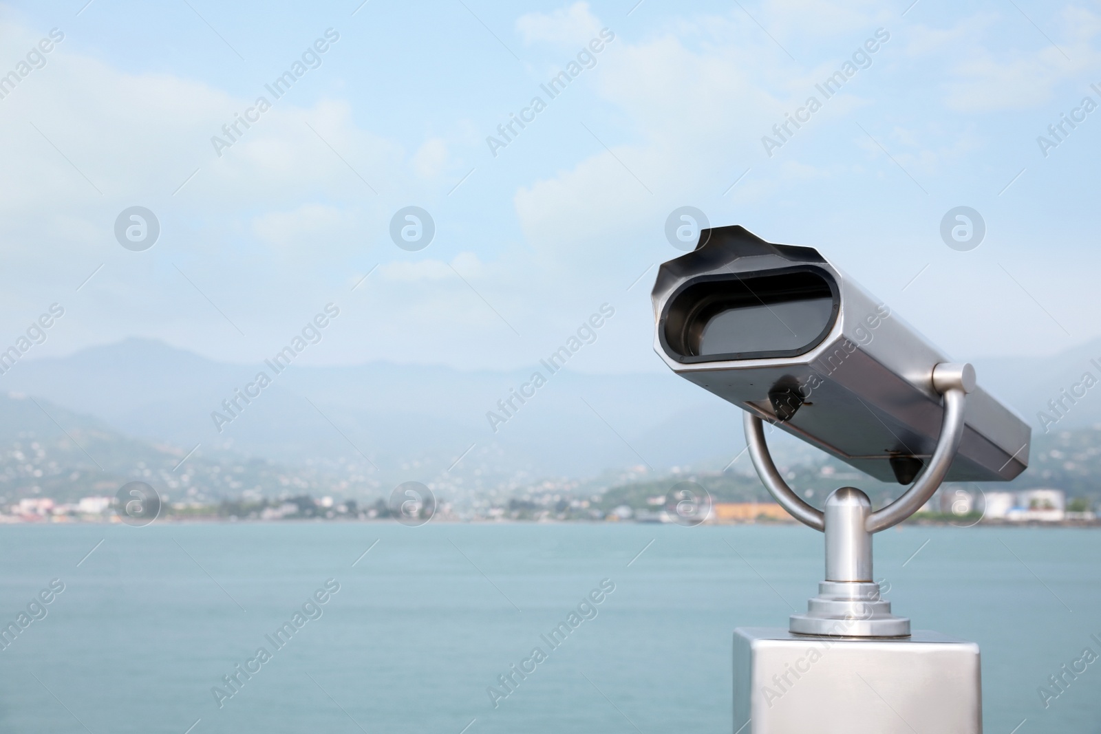 Photo of Metal tower viewer installed near sea, space for text. Mounted binoculars