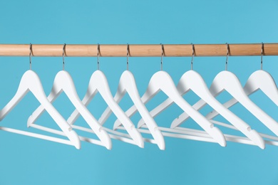 Wooden rack with clothes hangers on color background