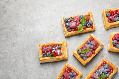 Fresh delicious puff pastry with sweet berries on grey table, flat lay. Space for text