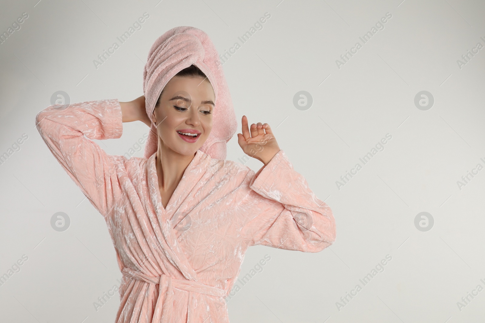 Photo of Beautiful young woman in bathrobe on light background