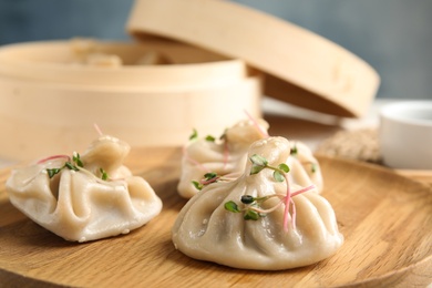 Wooden plate with tasty baozi dumplings on table, closeup